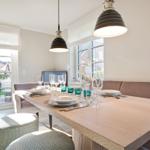 Dining area with wooden table, bench, and pendant lights. Access to terrace with garden furniture.