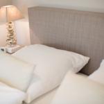 Bed headboard with white pillows and a lamp with shell base.