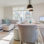 Living and dining area with sofa, table, and chairs. Windows and ceiling lights visible.