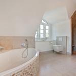 Bathroom with bathtub, toilet, and shower under sloped ceilings.