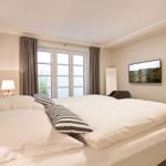 Bedroom with double bed, window, TV, and lamp.