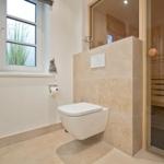 Bathroom with toilet and sauna in the background.