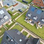 Aerial view of modern houses with gardens and parking areas.