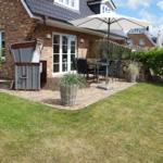 Terrace with table, chairs, and umbrella next to a garden house.