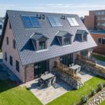 Modernes Haus mit Solaranlage und Gartenbereich mit Terrasse.