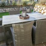 Terrassentisch mit sechs Stühlen und dekorativer Laterne auf Steinplatten