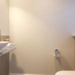 Badezimmer mit Waschbecken, Spiegel und Toilette.