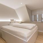 Schlafzimmer mit Doppelbett, Holzboden und Fenster mit Rollladen.
