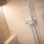Dusche mit modernem Duschsystem und beleuchtetem Badezimmerbereich.
