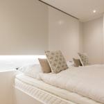 Schlafzimmer mit Bett, Kissen und Vorhängen an Fenster.