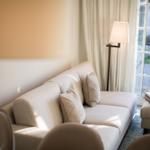 Ein Sofa mit Kissen steht vor einer Glastür. Daneben steht eine Stehlampe.