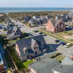 Aerial view of coastal village with houses, roads, and ocean in background.