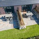 Terrace with tables and chairs, surrounded by stone walls and grass areas.