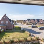 View through window onto street with houses and green areas
