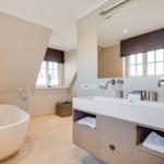Bath with freestanding bathtub and sink with mirror.