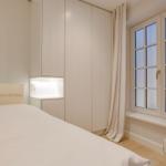 Bedroom with bed, wardrobe, and windowsill with vases.