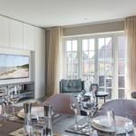 Dining room with TV, windows, and table with glasses and plates.