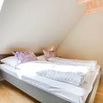 Bedroom with double bed, window, and wooden floor.