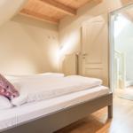 Bedroom with sloped ceiling, wooden floor, and bed with pillows.
