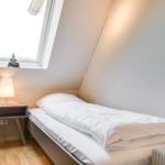 A bedroom with a double bed, nightstand, and skylight.