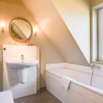 Bathroom with bathtub, sink, and mirror under sloped ceilings