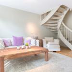 Living room with sofa, table, and spiral staircase.