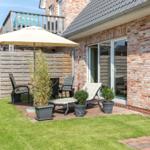 Backyard with patio, umbrella, lounge chairs, and plants. Wooden fence and brick wall.