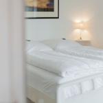 A bed with white bedding and a bedside lamp.