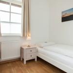 Bedroom with double bed, two nightstands, and window with curtains.