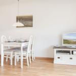 Dining area with table, chairs, and TV on media console.