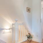 Staircase with white railings and flower basket on the floor.