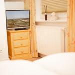 Bedroom with TV on wooden dresser, window with curtains and radiator.