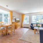 Living and dining area with wooden table, sofa, and large windows.