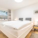 Bedroom with double bed, bedside table, and window with curtains.