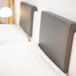 Two beds with gray headboards and white bedding.