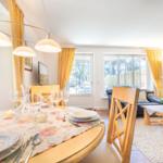 Dining table with chairs and windows in the living area.