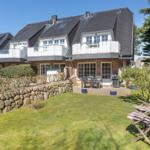 House with terrace, grill, and garden furniture. Stone garden and trees surround the property.