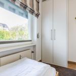 Bedroom with bed, wardrobe, and window overlooking greenery.