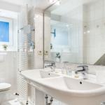 Bathroom with double sink, mirror, toilet, and window