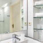 Bathroom with shower, mirror, and glass shelves for towels.