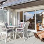 Terrace with table, chairs, and lounge under awning.