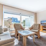 Living room with sofa, two chairs, and TV. Large window view to outdoor area.