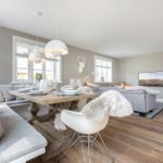 Essbereich mit Holztisch, Sitzbank und weißen Stühlen. Wohnbereich mit Sofa, Fernseher und Kamin.