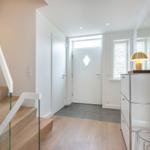 Hausgang mit Holztreppe, weißen Wänden und moderner Beleuchtung.