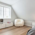 Schlafzimmer mit weißem Fellstuhl, Fenster und Bett