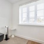 Sanitärzimmer mit Toilette, Fenster und Rollladen.