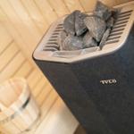 Sauna mit Steinofen und Holzwaschbecken.