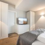 Schlafzimmer mit Bett, TV und Kleiderschränken.