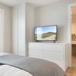 Schlafzimmer mit TV, Kleiderschrank und Blick in das Badezimmer.