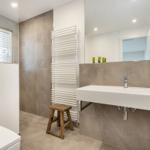 Badezimmer mit Waschbecken, Spiegel, Toilette und Heizkörper.